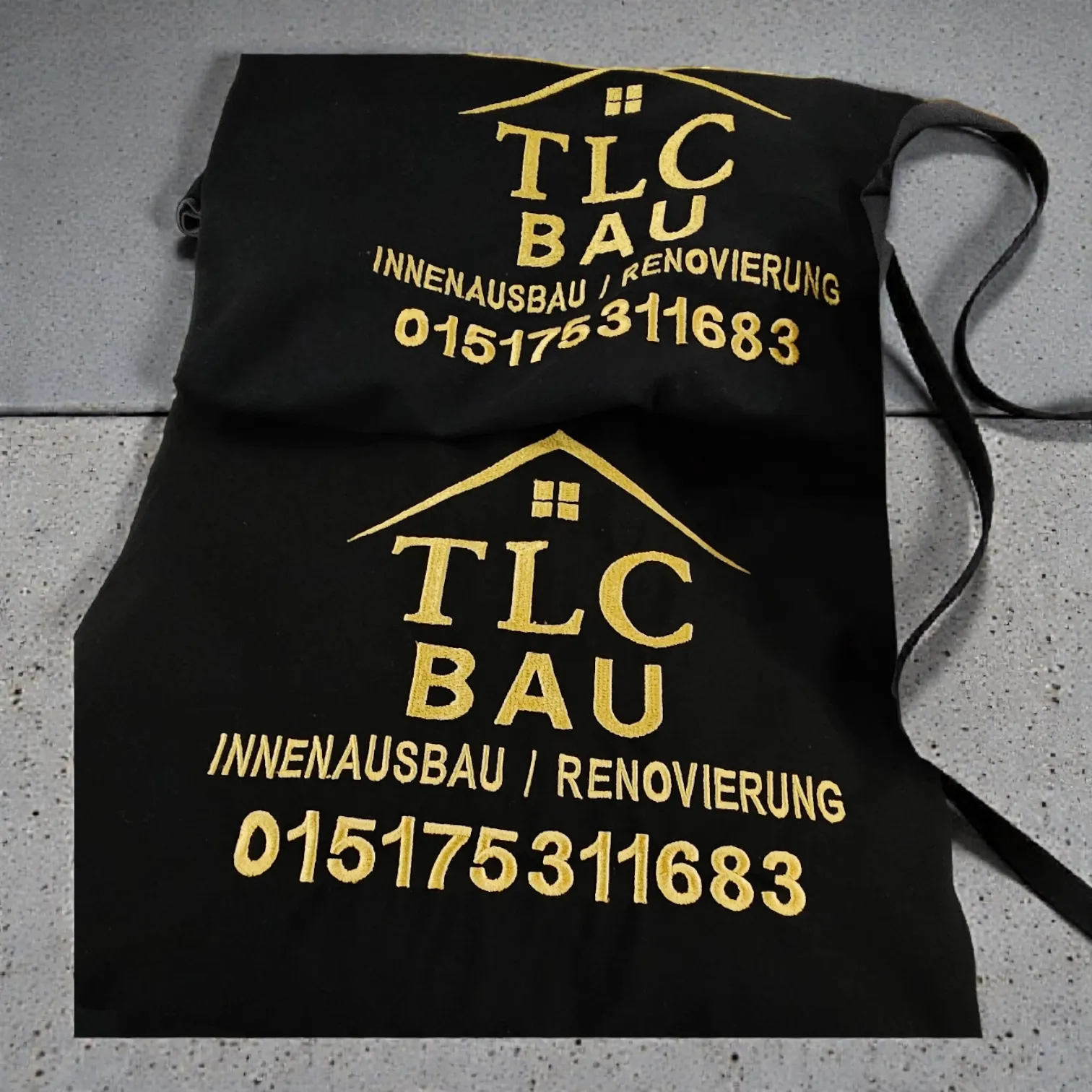 Goldene Stickerei auf schwarzen Schürzen für TLC Bau